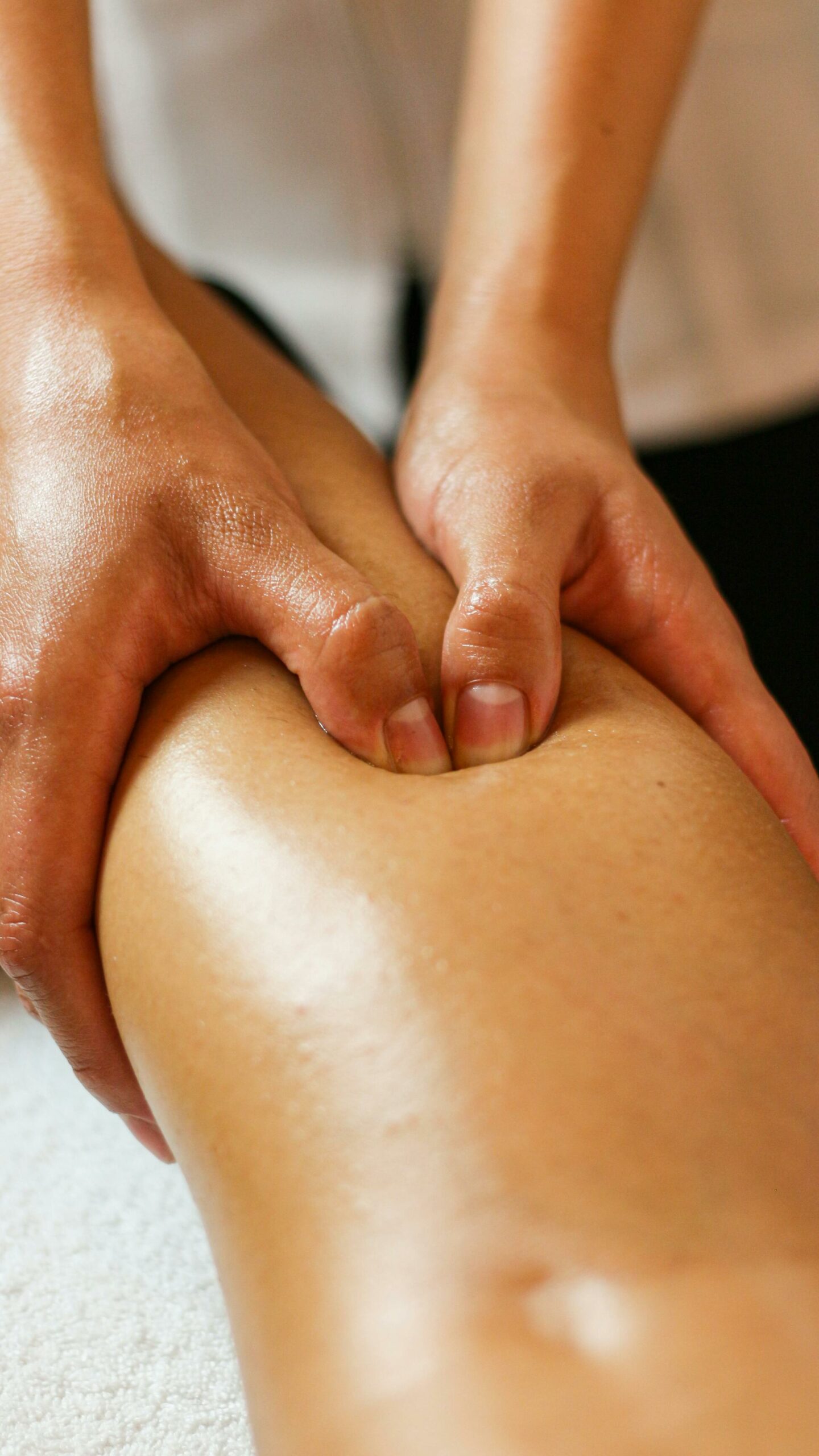 Home Close-up of hands applying pressure on a leg during a therapeutic massage session.